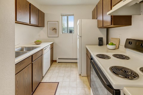 A kitchen with a white refrigerator, brown cabinets, and a white stove top.