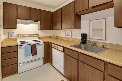 A kitchen with wooden cabinets and a white dishwasher.