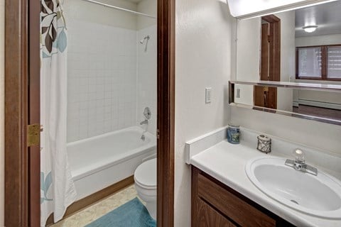A white sink in a bathroom with a white toilet and a white tub.