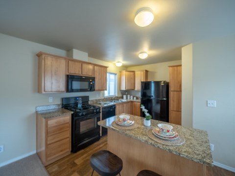 A kitchen with a granite counter top and wooden cabinets.