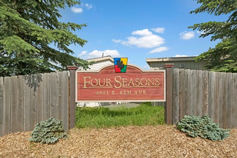A sign that says "Four Seasons" is in front of a fence.