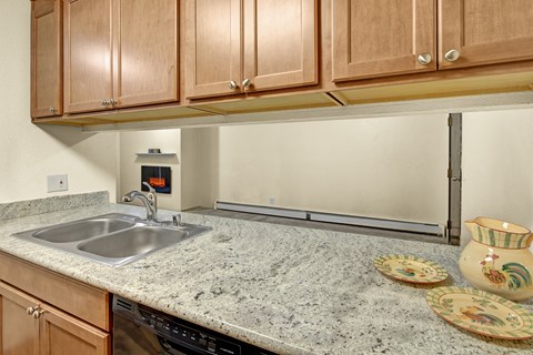 A kitchen with a granite countertop and wooden cabinets.