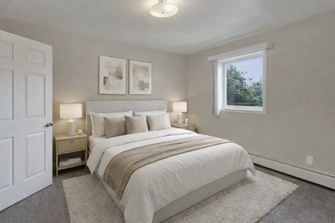 A bedroom with a large bed and two lamps on a nightstand.