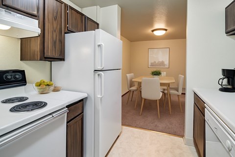 A kitchen with a white refrigerator and a dining table with chairs.