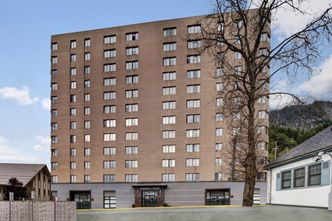 Tall exterior building of Mendenhall-Tower with rows of large windows and a clearly marked main entrance at street level.