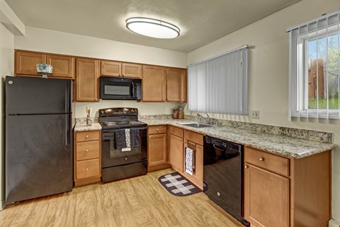 A kitchen with wooden cabinets and a black refrigerator.