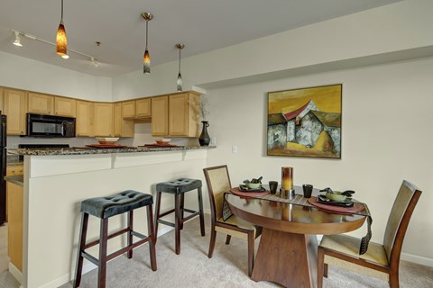 A kitchen with a table and chairs and a painting on the wall.