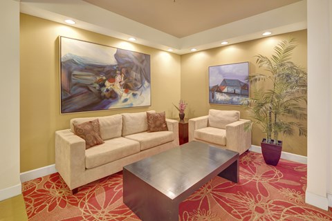A living room with a couch, chair, coffee table, and two paintings on the wall.