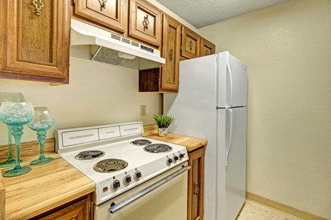 A white stove is in a kitchen with wooden cabinets.