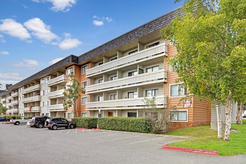 A large apartment building with a parking lot in front.