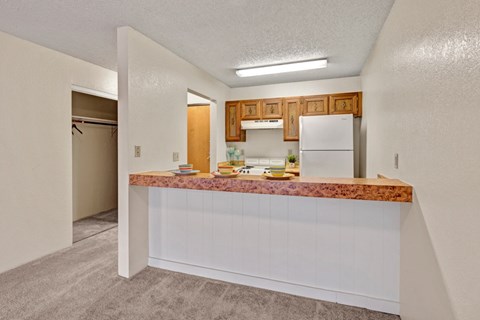 A kitchen with a white refrigerator and wooden cabinets.