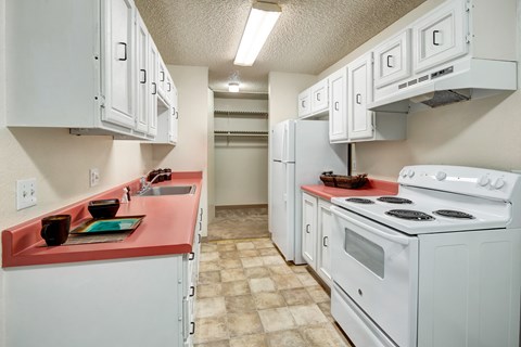 A kitchen with white cabinets and a red counter.
