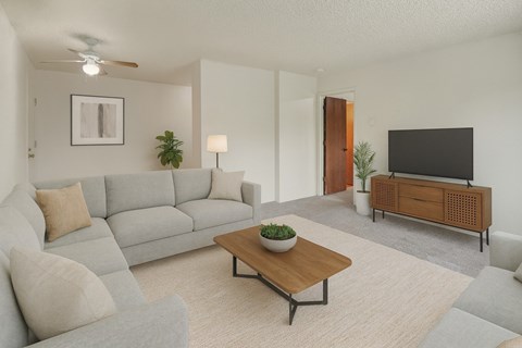 A living room with a grey couch, a wooden coffee table, and a flat screen TV.