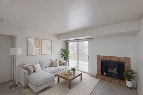 A living room with a grey couch, a fireplace, and a plant.