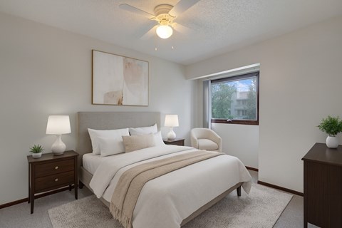 A bedroom with a bed, two lamps, a painting, and a window.