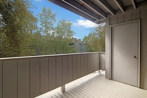A balcony with a door and a view of a building in the distance.