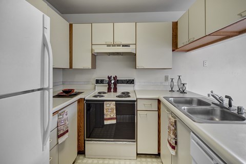 A kitchen with a white refrigerator, a black oven, and a stove top.