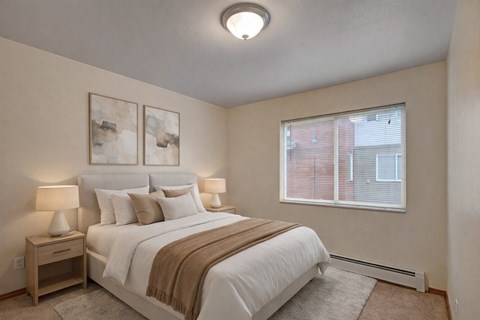 A bedroom with a large bed and two lamps.