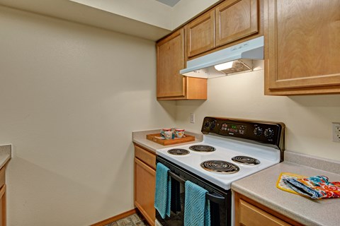 A kitchen with a stove top oven and wooden cabinets.