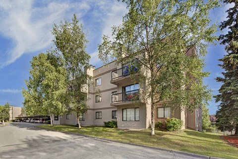 A large apartment building with a parking lot in front.