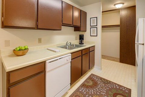 A kitchen with brown cabinets and a white dishwasher.