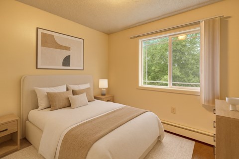A bedroom with a large bed and a window overlooking trees.