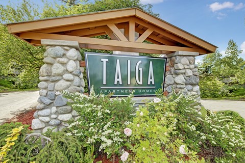 A sign that says Taiga Apartments in front of a building.
