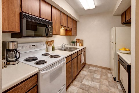A kitchen with a white stove top oven and white countertops.