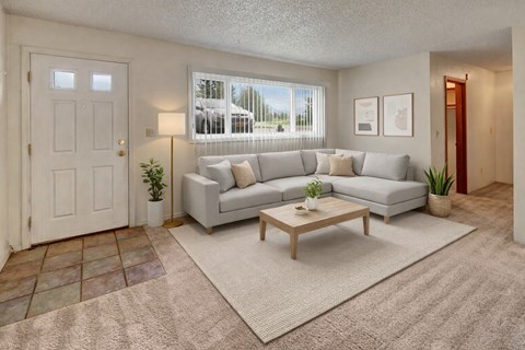 A living room with a grey couch, a coffee table, and a white door.