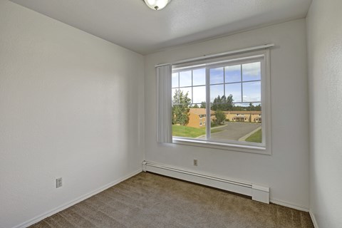 A room with a window showing a view of a street and houses.