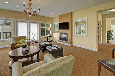 A living room with a brown carpet and a chandelier.