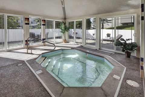 A cozy indoor hot tub here at The Highlands Luxury surrounded by plants, and lovely warm sunlight gleaming inside the jacuzzi space.