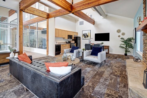 A modern living room with a black couch and a wooden beam ceiling.
