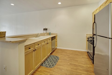 A kitchen with wooden cabinets and a stainless steel refrigerator.