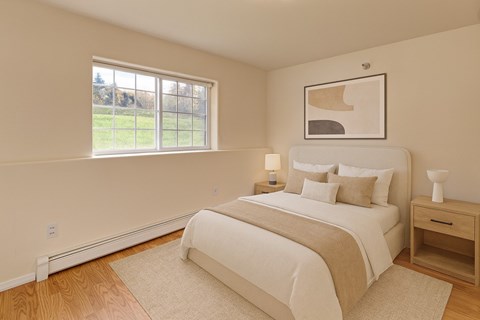 A bedroom with a large bed, nightstand, and window.
