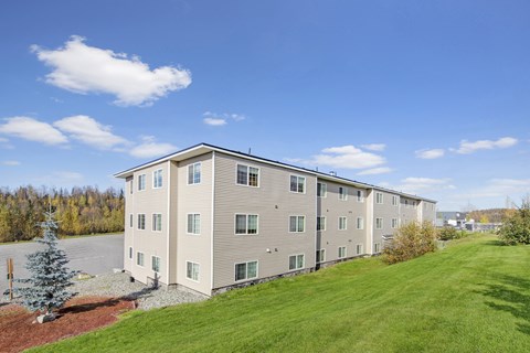 A large apartment building with a green lawn in front.