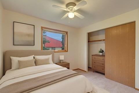 A bedroom with a bed, nightstand, and a window.