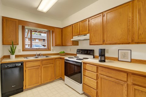 A kitchen with wooden cabinets and a black dishwasher.