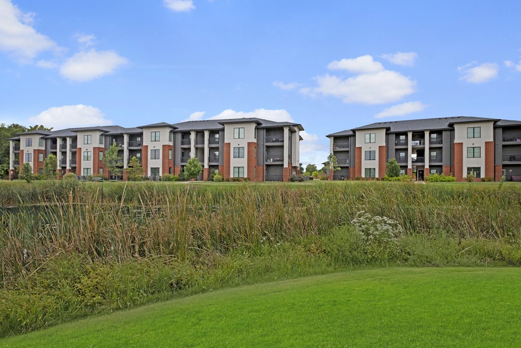 a row of apartment buildings overlooking a green field