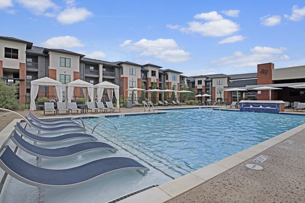 a swimming pool with several lounge chairs and an apartment building