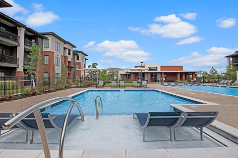 A swimming pool with a slide and lounge chairs in front of apartment buildings.