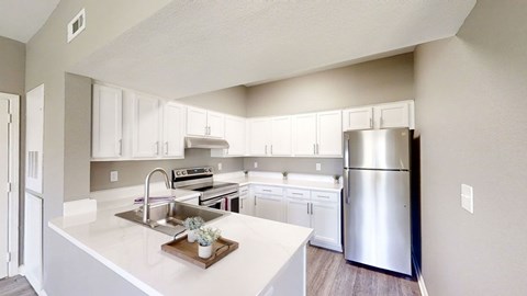 A modern kitchen with a stainless steel refrigerator and white countertops.