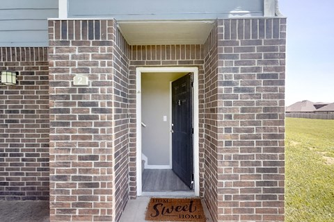 A house entrance with a mat that says "Sweet Home".