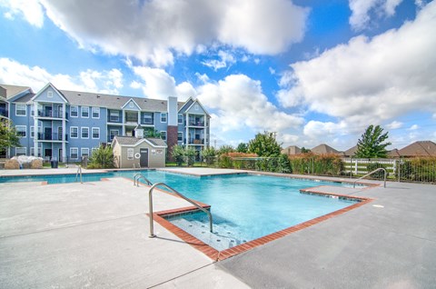 A large swimming pool in front of a multi-story apartment building.