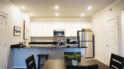 A kitchen with a table and chairs in front of it.
