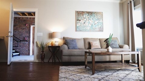 A living room with a couch, a table, and a painting on the wall.