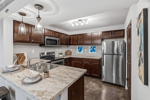 A kitchen with brown cabinets and a granite counter top.