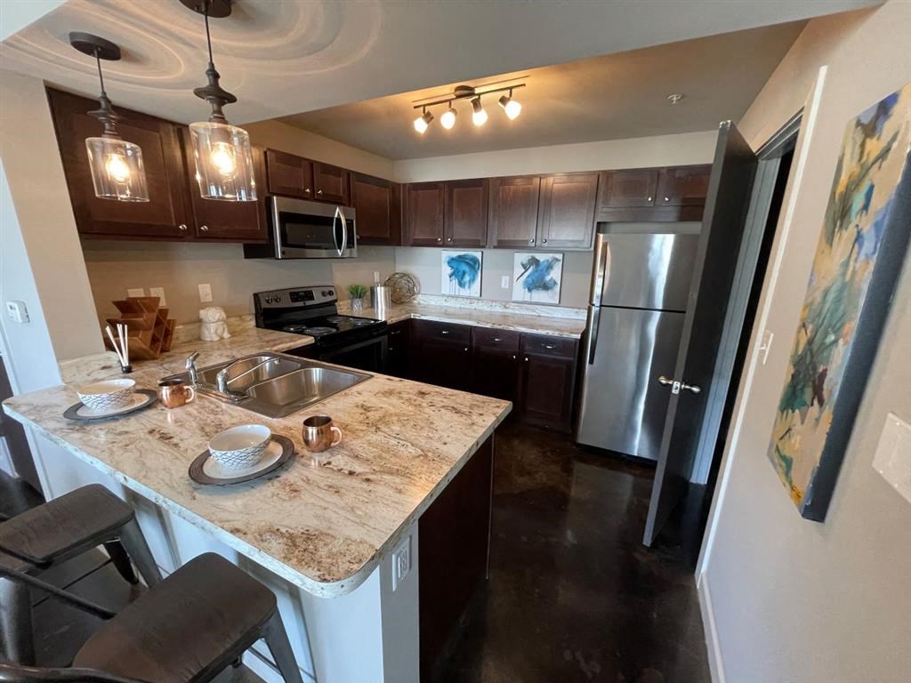 A kitchen with a marble countertop and stainless steel appliances.
