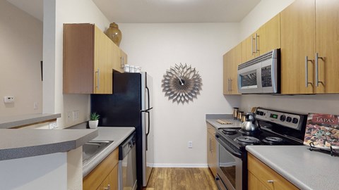 A fully furnished kitchen with a microwave, oven, refrigerator, sink, and stovetop.