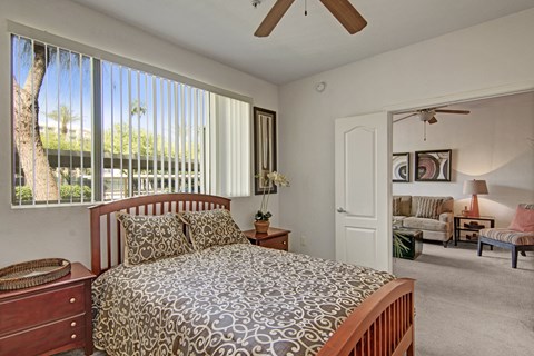 A bedroom with a bed, dresser, and window with blinds.